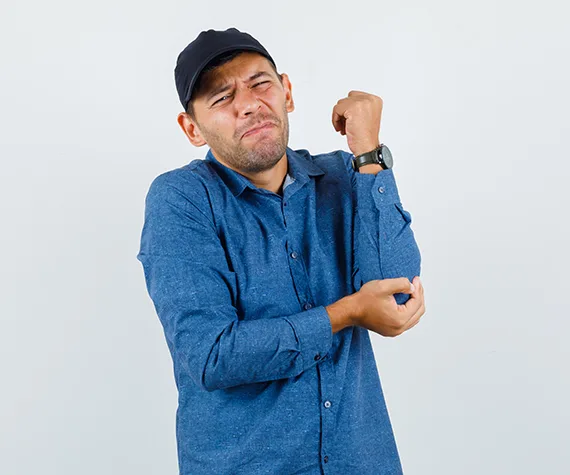 Person holding the inner elbow, a common area of pain in cubital tunnel syndrome, treated at IROSM in Fort Lauderdale